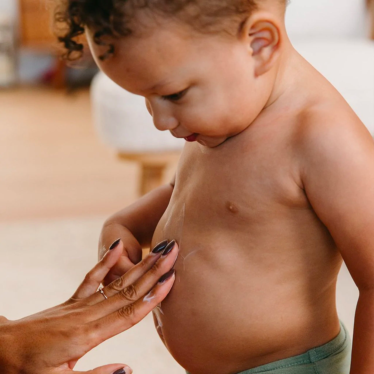 Mom applying the Everyday Lotion on her baby boy's belly.